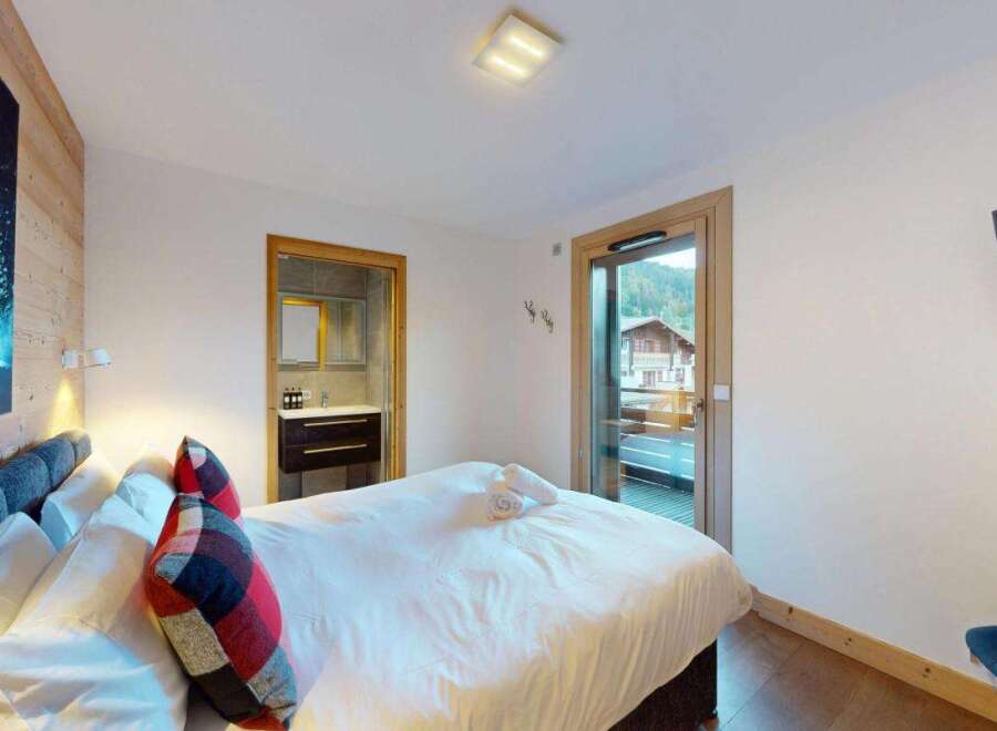 Experience ultimate comfort in this beautifully appointed bedroom, featuring a plush king-size bed adorned with decorative pillows and crisp white linens.