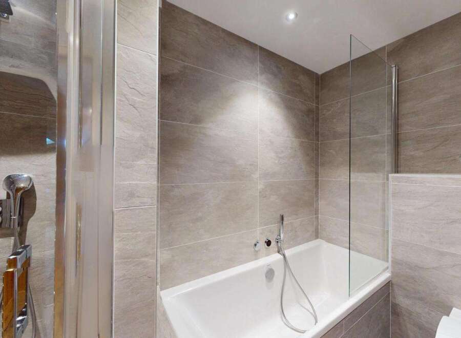 Experience modern luxury in this stunning bathroom, featuring a sleek bathtub and a separate shower enclosure with a rainfall showerhead.