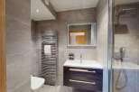 This modern bathroom features a sleek vanity with ample storage, a spacious walk-in shower with a rainfall showerhead, and a heated towel rack.