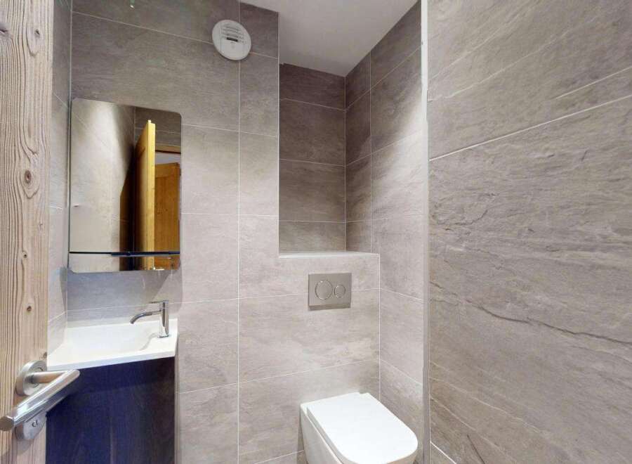 This modern bathroom features a sleek white sink with a chrome faucet, complemented by a large mirrored cabinet.