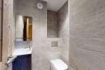 This modern bathroom features a sleek white sink with a chrome faucet, complemented by a large mirrored cabinet.