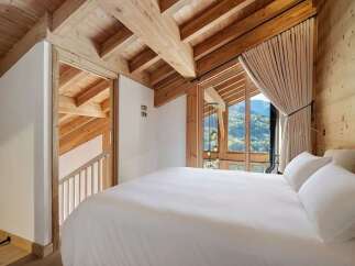 Experience luxury mountain living in this stunning bedroom featuring exposed wooden beams and a vaulted ceiling.
