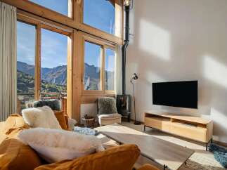 Experience breathtaking mountain views from this stunning living room, featuring a cozy fireplace and a large flat-screen TV.