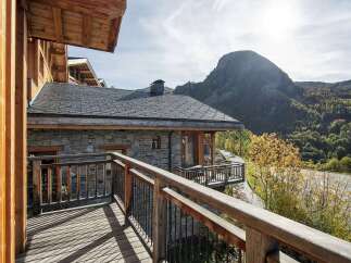 Experience the charm of mountain living with this stunning property, featuring a rustic stone facade and a spacious wooden balcony offering breathtaking views.