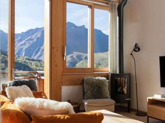 Experience breathtaking mountain views from this cozy living room, featuring a modern wood-burning stove and comfortable seating.
