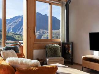 Experience breathtaking mountain views from this stunning living room, featuring a cozy fireplace and large windows that flood the space with natural light.