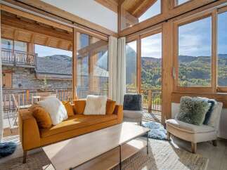 Experience breathtaking mountain views from this stunning living room, featuring a cozy orange sofa adorned with plush white pillows.