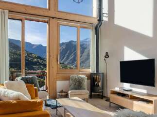 Experience breathtaking mountain views from this stunning living room, featuring a cozy fireplace and large windows that flood the space with natural light.