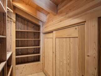 Discover this charming wooden closet, featuring a built-in shelving unit perfect for organizing your belongings.