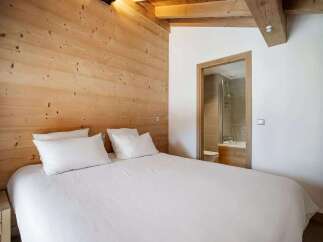 Experience cozy mountain living in this charming bedroom featuring warm, natural wood paneling on the walls and ceiling.