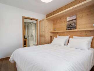 Experience cozy mountain living in this charming bedroom featuring a comfortable queen-sized bed with crisp white linens.