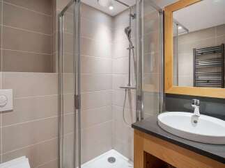 This modern bathroom features a sleek glass-enclosed shower with a rainfall showerhead, perfect for a refreshing start to your day.