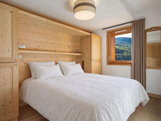Experience cozy mountain living in this charming bedroom, featuring a comfortable queen-size bed dressed in crisp white linens.