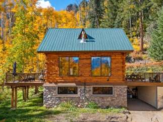 Nestled amidst vibrant autumn foliage, this charming log cabin offers a serene mountain retreat.