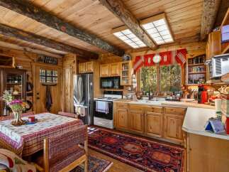 Experience rustic charm in this cozy log cabin kitchen, featuring warm wooden beams, natural light, and a charming dining area perfect for intimate meals.