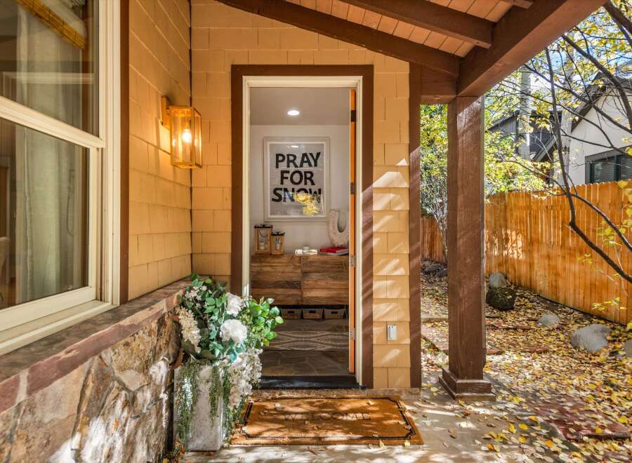 Welcome guests with a charming entryway featuring a 'Pray for Snow' sign and a beautiful floral arrangement.