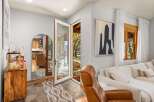 Step into a welcoming entryway featuring a large arched mirror reflecting a cozy kitchen and a plush leather armchair.