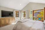 Experience ultimate comfort in this master bedroom, featuring a large flat-screen TV mounted above a charming wooden media console.