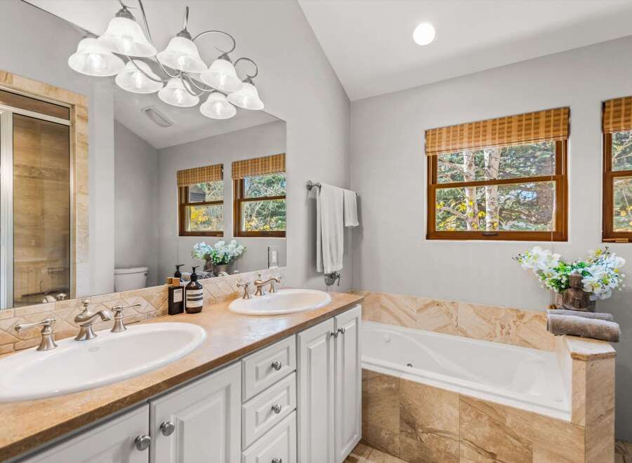 This luxurious bathroom features a spacious double vanity with elegant silver fixtures and a large mirror reflecting the natural light from the windows.