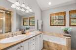 This luxurious bathroom features a spacious double vanity with elegant silver fixtures and a large mirror reflecting the natural light from the windows.