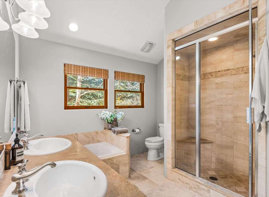 This luxurious bathroom features a spacious walk-in shower with elegant travertine tile and a built-in bench.