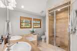 This luxurious bathroom features a spacious walk-in shower with elegant travertine tile and a built-in bench.