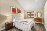 Experience comfort and style in this inviting bedroom, featuring a plush queen-size bed adorned with crisp white linens and a cozy throw blanket.