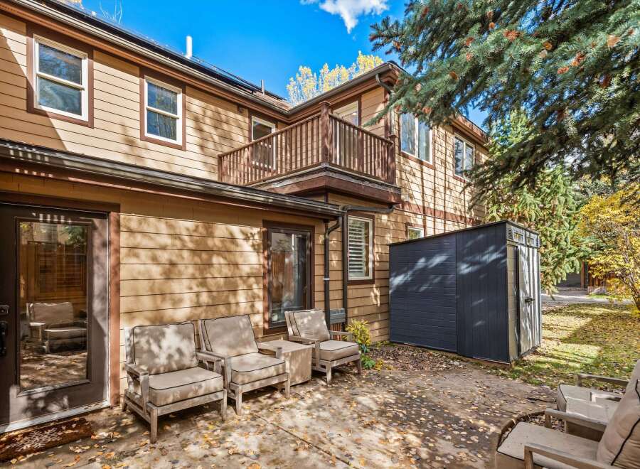 Enjoy outdoor living in this charming backyard featuring a concrete patio adorned with fallen leaves, perfect for a serene autumn setting.