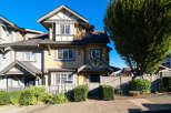 Charming townhouse featuring a classic yellow siding exterior with contrasting grey trim and a dark shingled roof.
