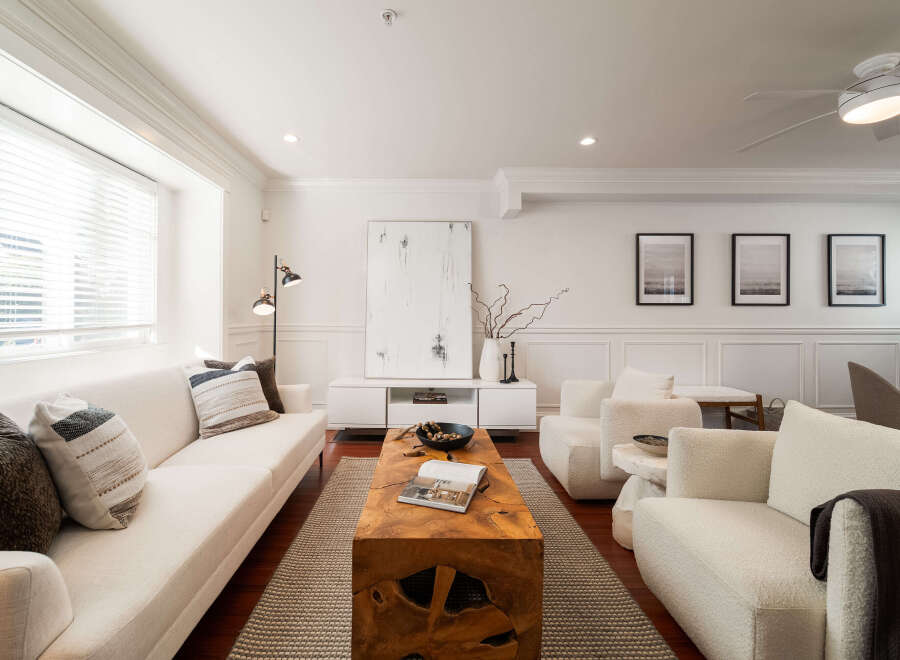 Step into this elegantly designed living room, featuring a plush white sectional sofa adorned with decorative pillows and a striking live-edge wood coffee table.