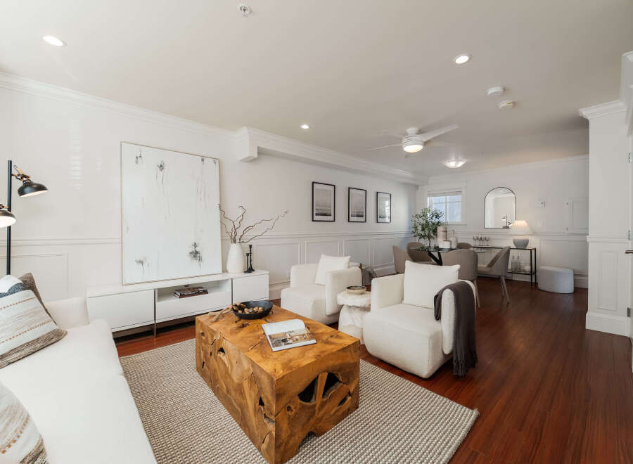 This beautifully appointed living space features a plush white sofa and two matching armchairs, creating a cozy and inviting atmosphere.