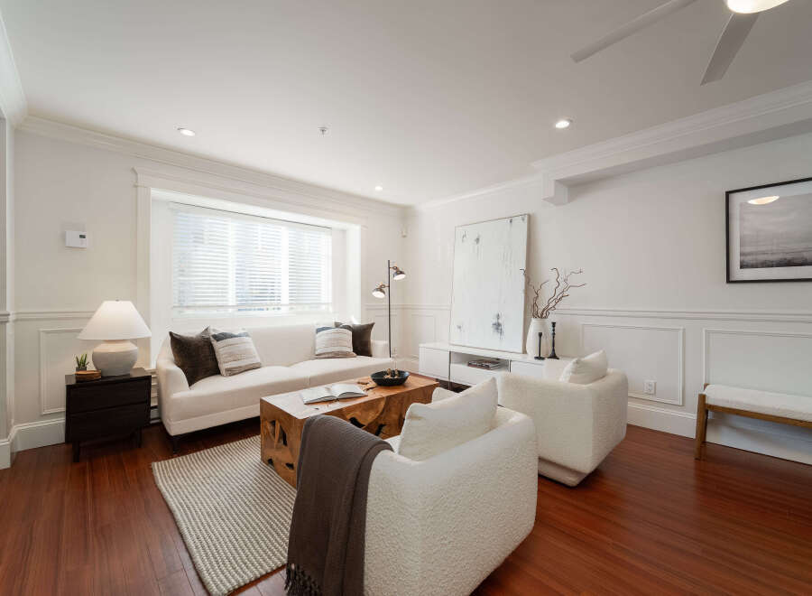 Step into this inviting living room, featuring a plush white sofa adorned with decorative pillows, perfect for relaxation.