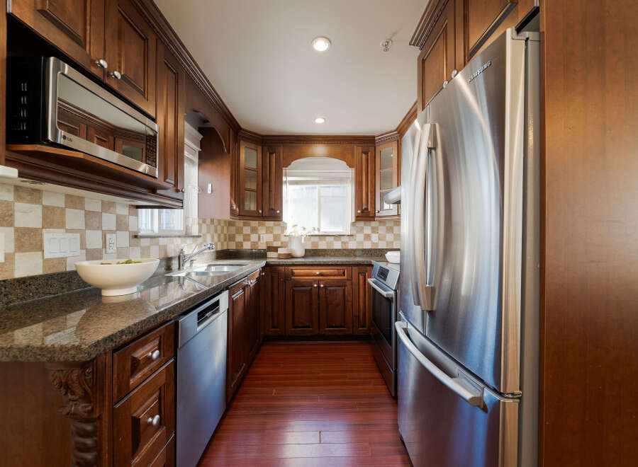 This kitchen boasts rich, dark wood cabinetry complemented by sleek stainless steel appliances, including a Samsung refrigerator and an LG microwave.