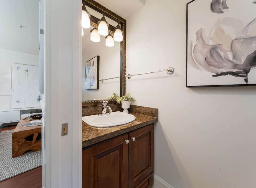 This elegant powder room features a granite-topped vanity with a white undermount sink and a polished chrome faucet.