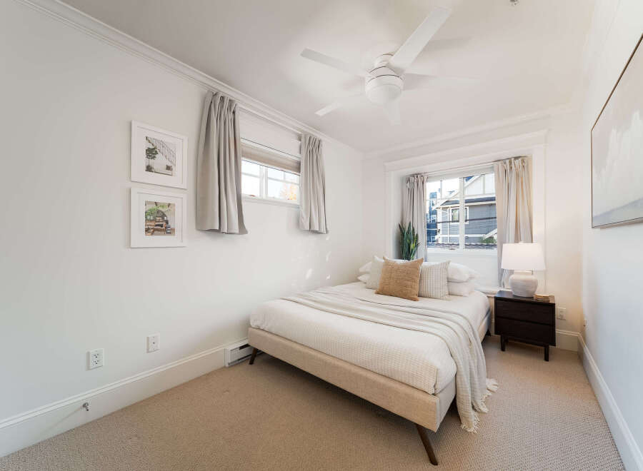 This bright and airy bedroom features a comfortable queen-size bed adorned with plush pillows and a cozy throw blanket.