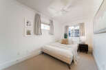 This bright and airy bedroom features a comfortable queen-size bed adorned with plush pillows and a cozy throw blanket.