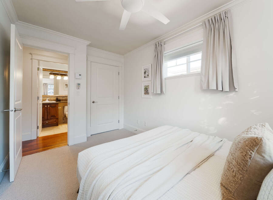 Step into this inviting bedroom, featuring a plush carpet and a comfortable bed adorned with crisp white linens.
