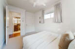 Step into this inviting bedroom, featuring a plush carpet and a comfortable bed adorned with crisp white linens.
