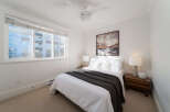 This cozy bedroom features a comfortable queen-size bed dressed in crisp white linens and a dark gray throw blanket.
