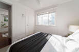 Step into this bright and airy bedroom, featuring a comfortable bed adorned with a stylish dark grey throw blanket.