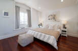 Experience serene comfort in this beautifully appointed bedroom, featuring a plush queen-size bed dressed in crisp white linens with subtle grey stripes.
