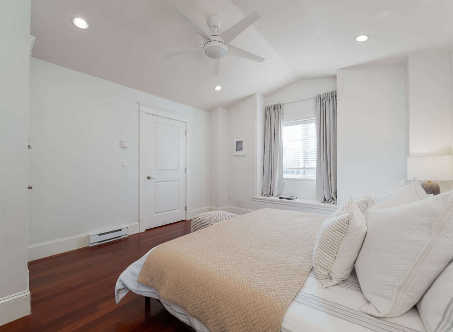 Experience comfort and style in this beautifully appointed bedroom, featuring a plush bed adorned with crisp white linens and a textured beige quilt.