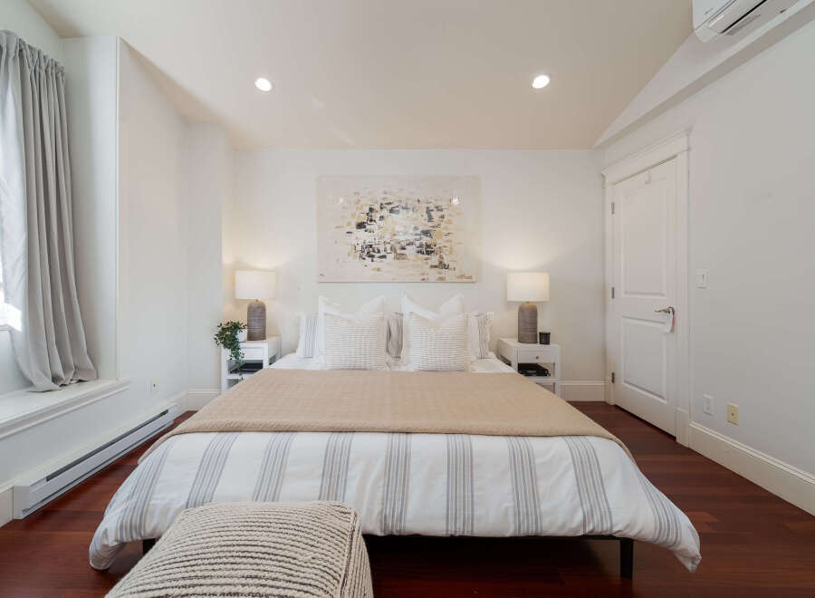 Experience comfort and style in this beautifully appointed bedroom, featuring a plush king-sized bed adorned with crisp white linens and decorative pillows.