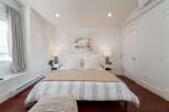 Experience comfort and style in this beautifully appointed bedroom, featuring a plush king-sized bed adorned with crisp white linens and decorative pillows.