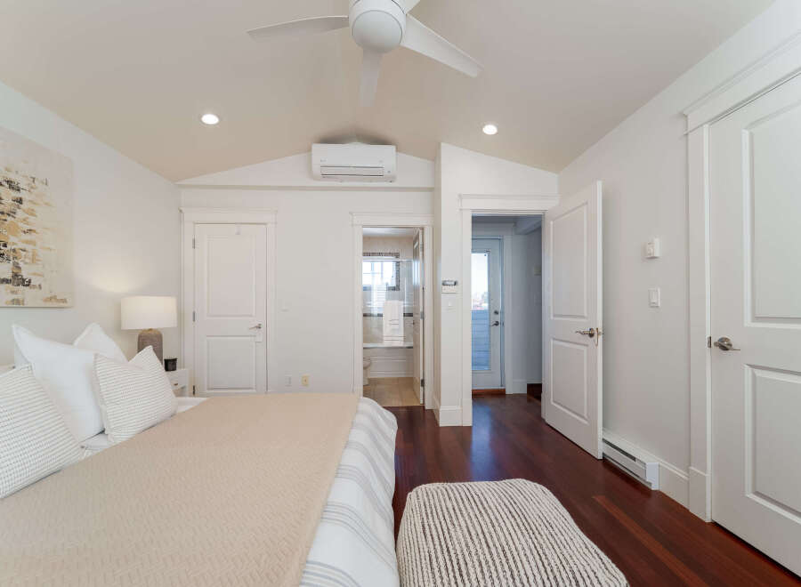 Experience modern comfort in this beautifully appointed bedroom, featuring a plush bed adorned with crisp white linens and decorative pillows.