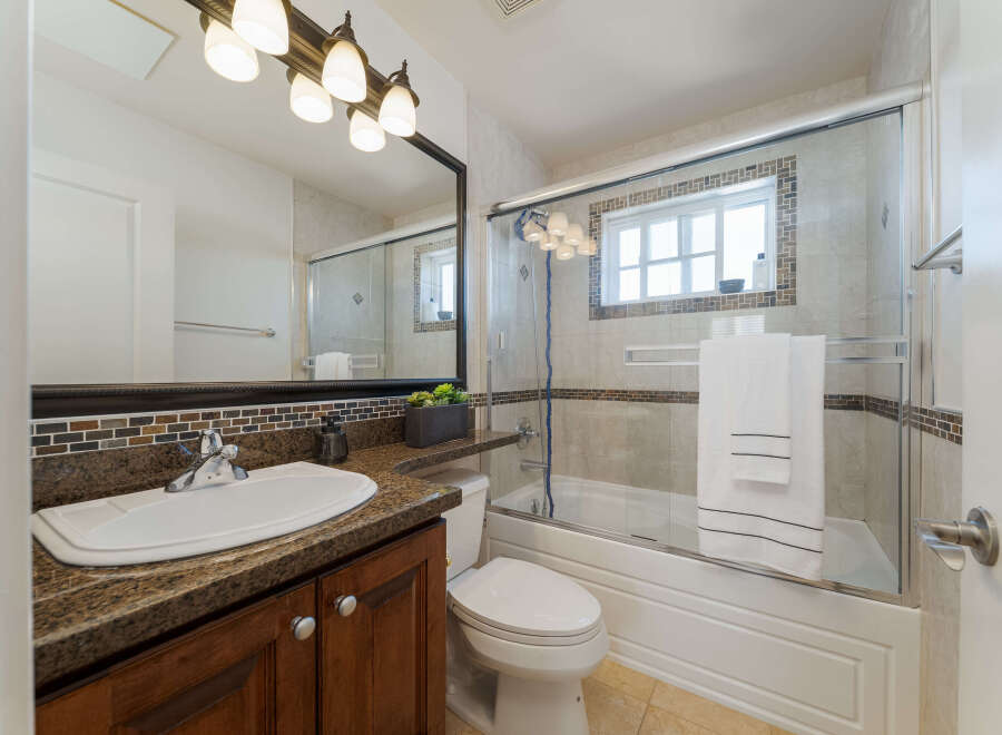 This charming bathroom features a granite-topped vanity with a white sink and a dark wood cabinet below.