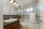 This charming bathroom features a granite-topped vanity with a white sink and a dark wood cabinet below.