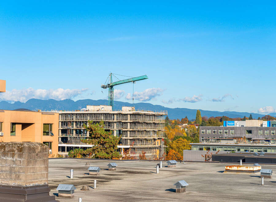This image captures a vibrant urban landscape with a focus on ongoing construction and existing buildings under a clear blue sky.