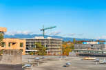 This image captures a vibrant urban landscape with a focus on ongoing construction and existing buildings under a clear blue sky.