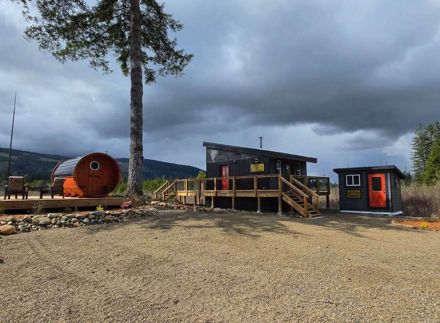 Discover this unique property featuring a modern cabin with a wraparound deck, a charming barrel sauna, and a separate outbuilding.